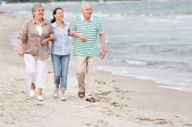 Senioren mit Pflegerin spazieren am Strand