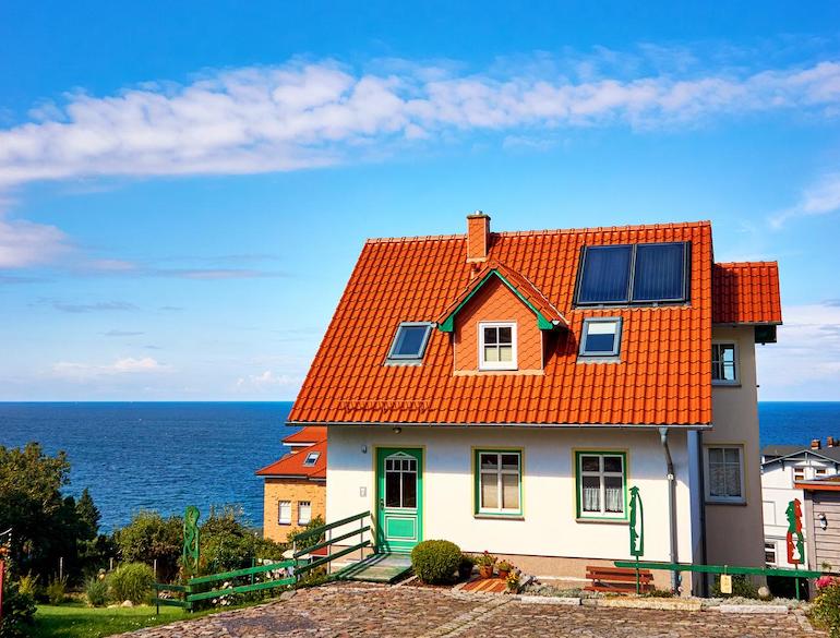 Ein weißes Einfamilienhaus am Meer vor blauem Himmel