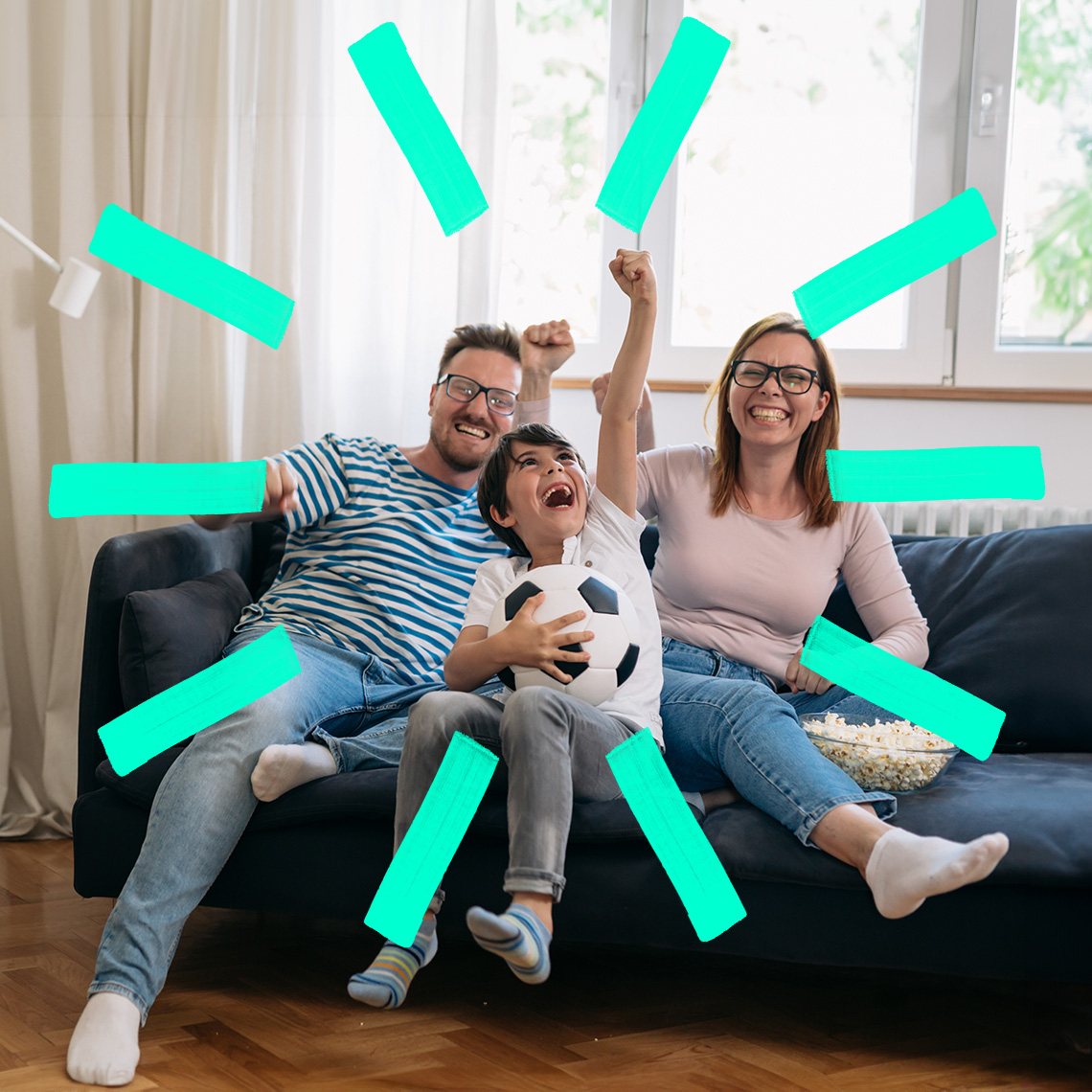 Eine Familie feiert, während sie auf einer Couch Fußball schaut
