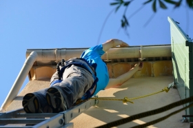 Ein Mann repariert die Dachrinne
