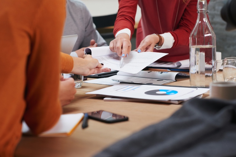 Drei Personen diskutieren am Tisch über Zinsstatistiken