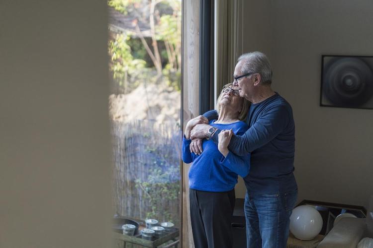 Rentner-Ehepaar steht am Fenster