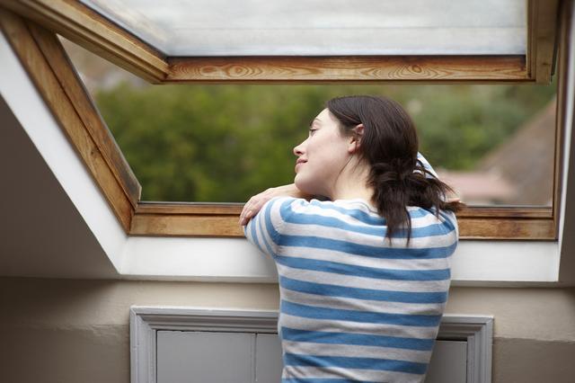 Frau sieht aus dem Fenster einer Dachschräge